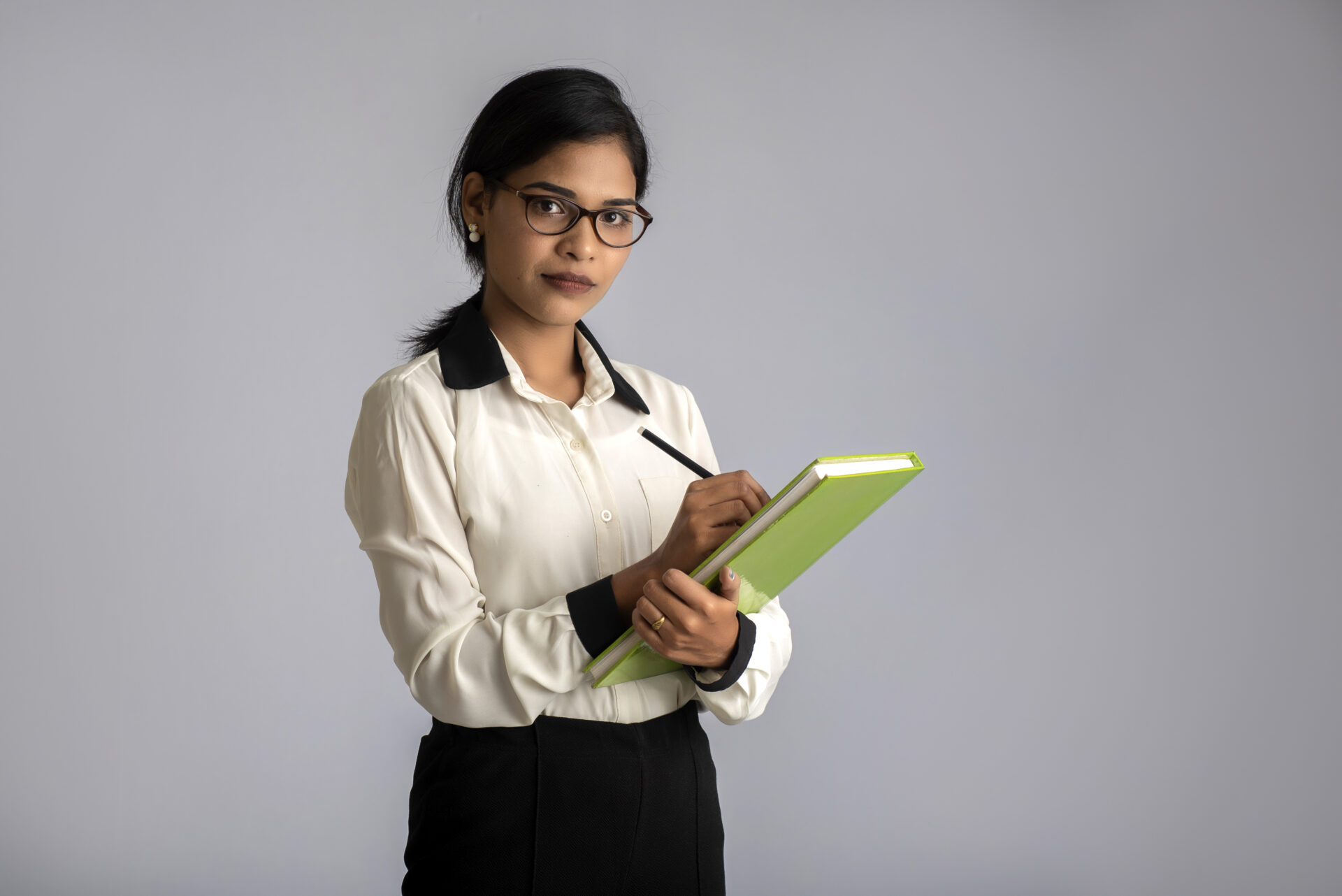 Pretty young girl holding book and posing on grey background