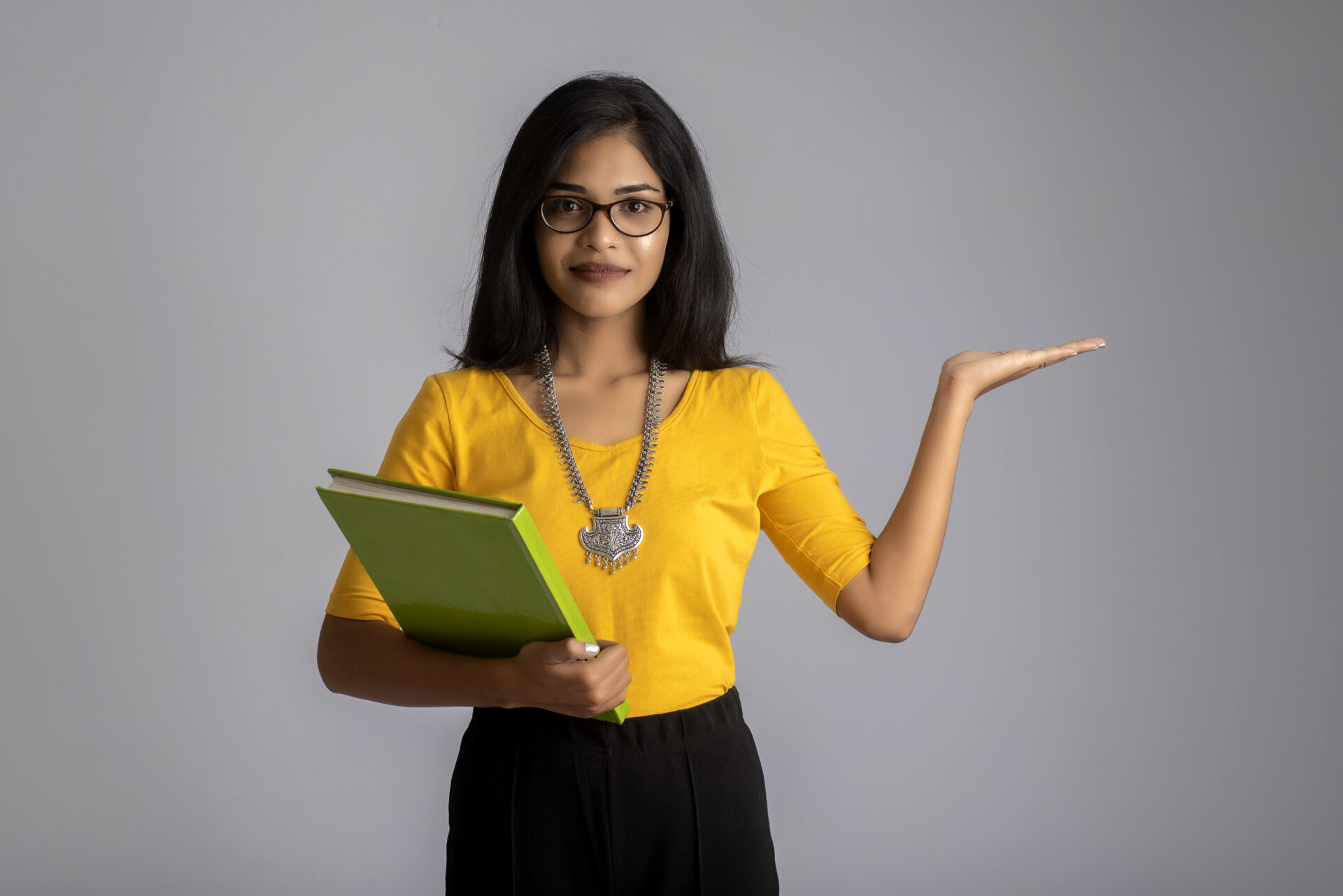 Pretty young girl posing with the book on grey background